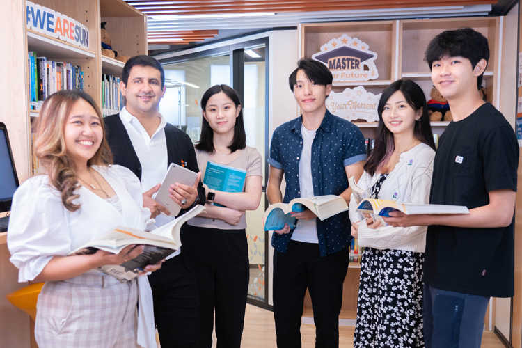 A group of people standing in the University of Sunderland in Hong Kong’s library.

