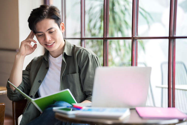 Young Asian businessman online learning at coffee shop.