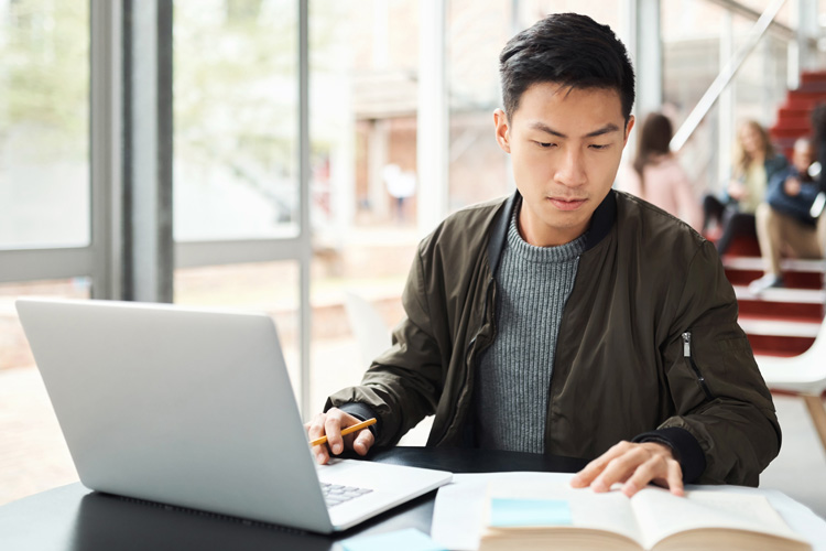 Asian man research on pc with language report writing.