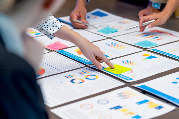 A group of people hands on a board room table at a business presentation.